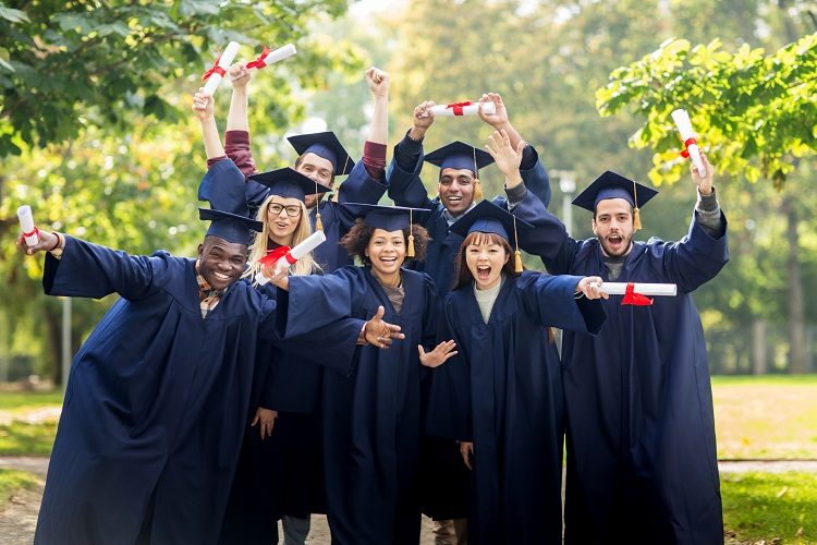education, graduation and people concept - group of happy international students in mortar boards and bachelor gowns with diplomas